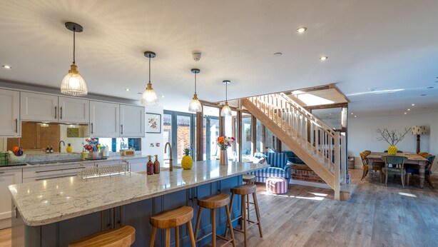 Una cocina amplia con una isla grande, taburetes de madera y luces colgantes.