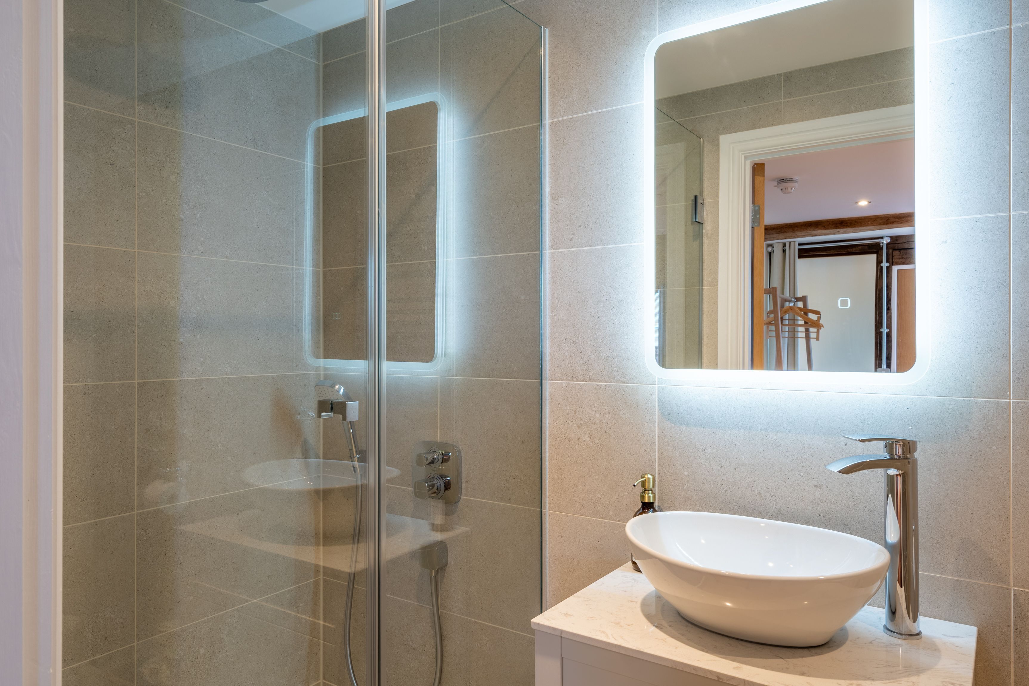 Une salle de bain moderne avec une douche à parois de verre, un lavabo blanc et un miroir au-dessus du lavabo.