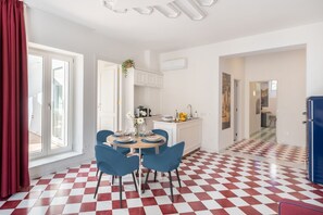 A modern kitchen with white cabinets, a dining area with blue chairs, and a checkered floor.