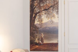 Una pintura que muestra dos figuras junto a un lago, con una montaña al fondo.