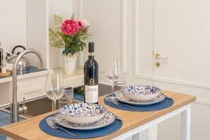 A dining table set with two plates, a wine bottle, and a vase of flowers. - Exclusive Home in Sorrento center for Families (Sorrento)