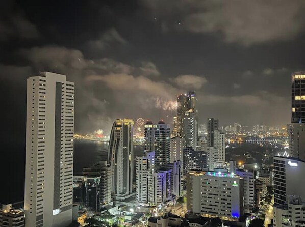 A nighttime cityscape with high-rise buildings and a view of the waterfront.