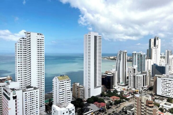 A cityscape with tall buildings, a clear sky, and a view of the ocean. - Panoramic High-Rise Oceanview Condo in Bocagrande (Bocagrande)