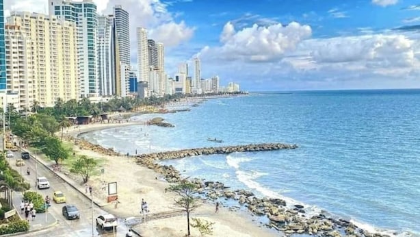 A coastal cityscape with high-rise buildings, a sandy beach, and a rocky shoreline. - Panoramic High-Rise Oceanview Condo in Bocagrande (Bocagrande)