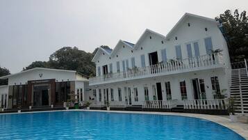 Un hotel con una piscina grande, varios balcones y fachada blanca.