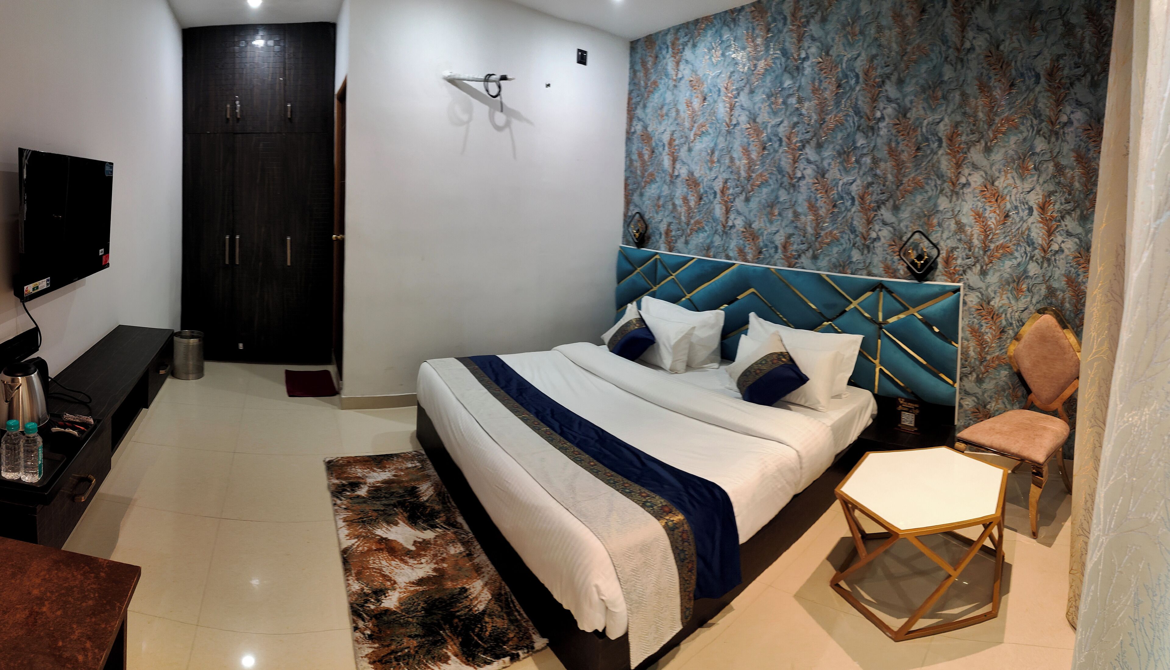 Quarto de hotel com cama, televisão, escrivaninha e cadeira.