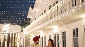 A couple in traditional wedding attire standing in an outdoor area with string lights overhead. - The Pinaki resort & Club (Varanasi)