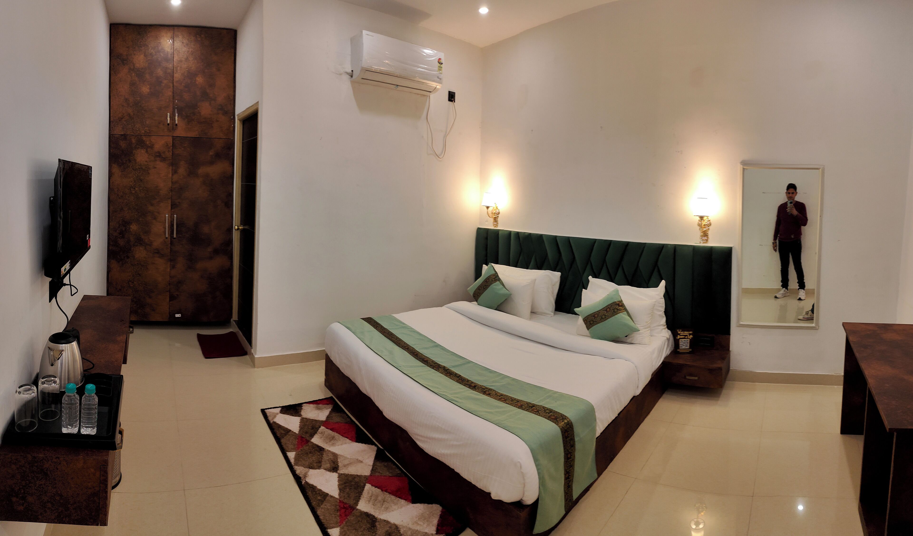 Une chambre d’hôtel équipée d’un lit, d’une télévision, d’un bureau, d’un miroir et d’un appareil de climatisation.