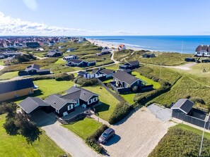 Een kustgebied met huizen, een strand en een vuurtoren op de achtergrond.