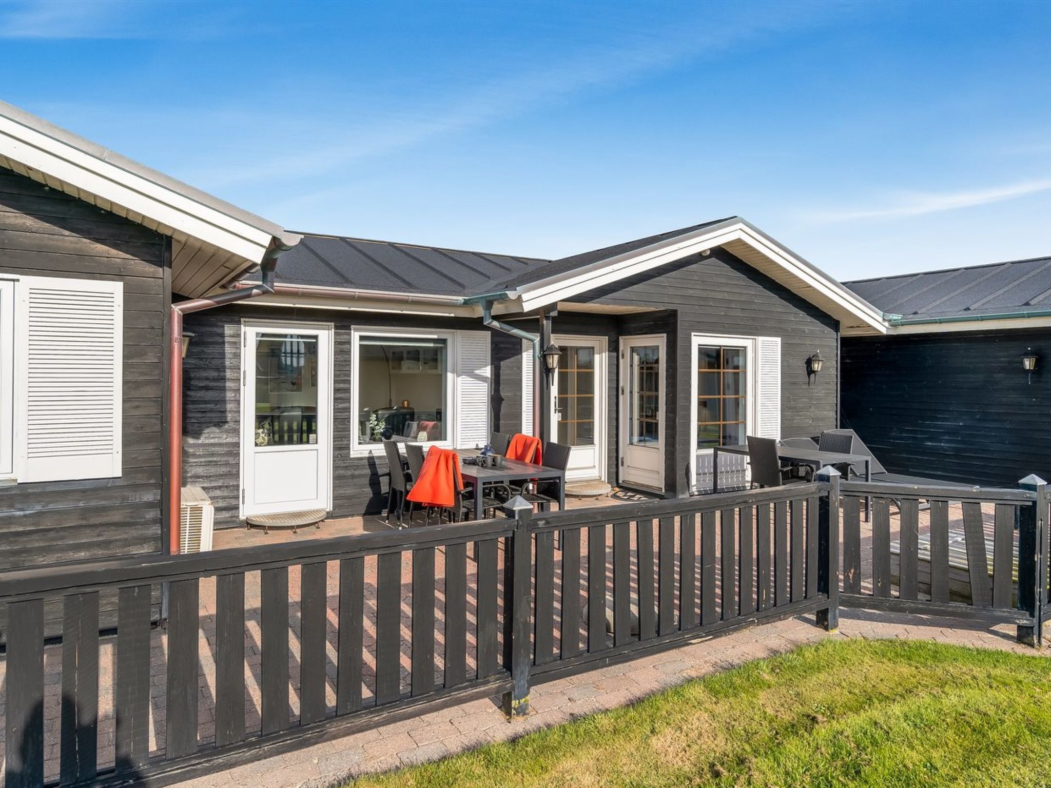 A modern RV with a covered patio area, including a barbecue setup and outdoor seating.