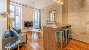 Un espace de vie moderne comprenant un coin cuisine, un plancher en bois et un mur d’accent en pierre.