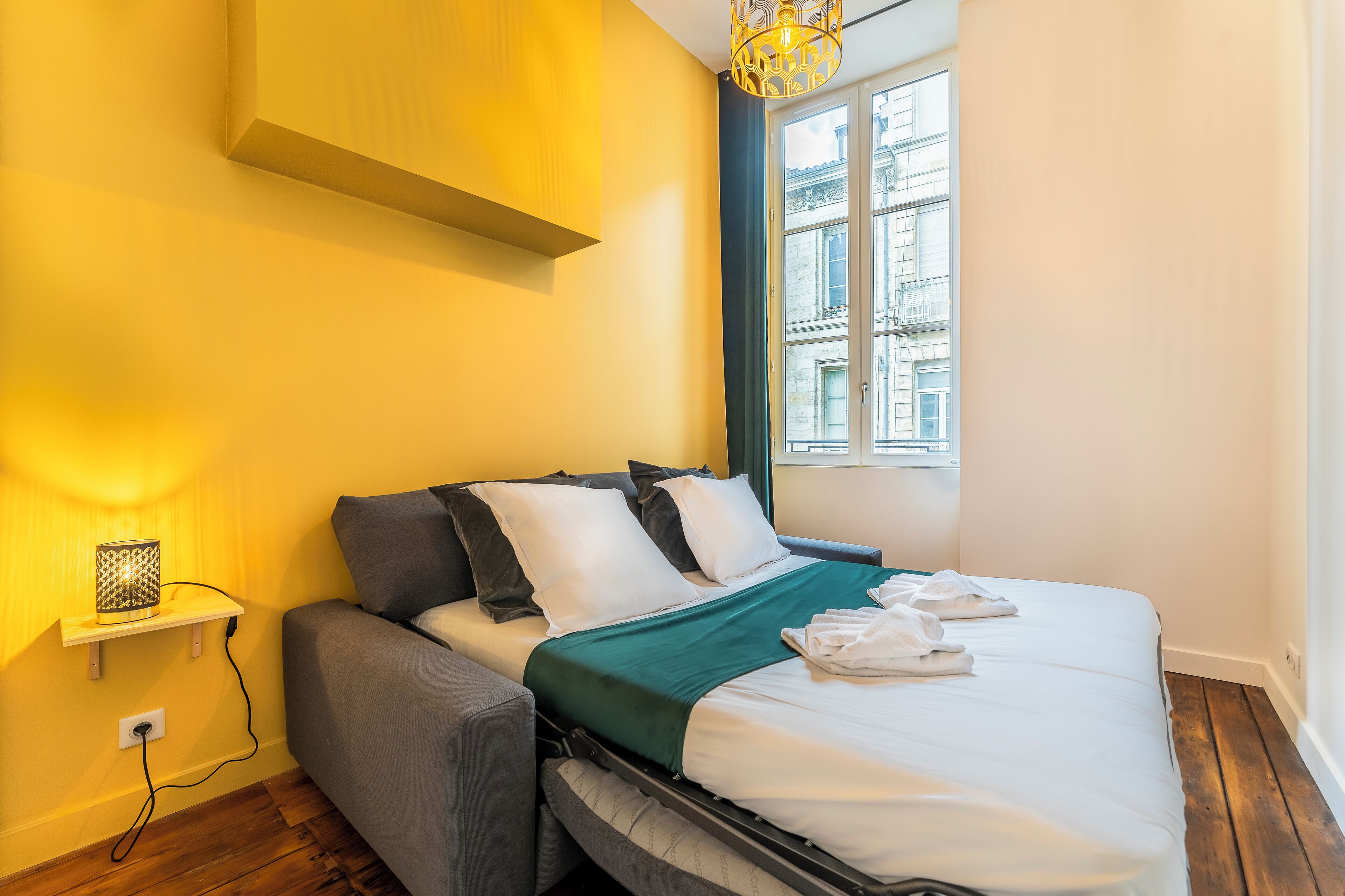 Une chambre à coucher de taille réduite, comprenant un lit, une table de chevet et une fenêtre.