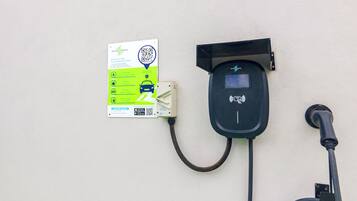An electric vehicle charging station with a QR code and instructions on a sign.