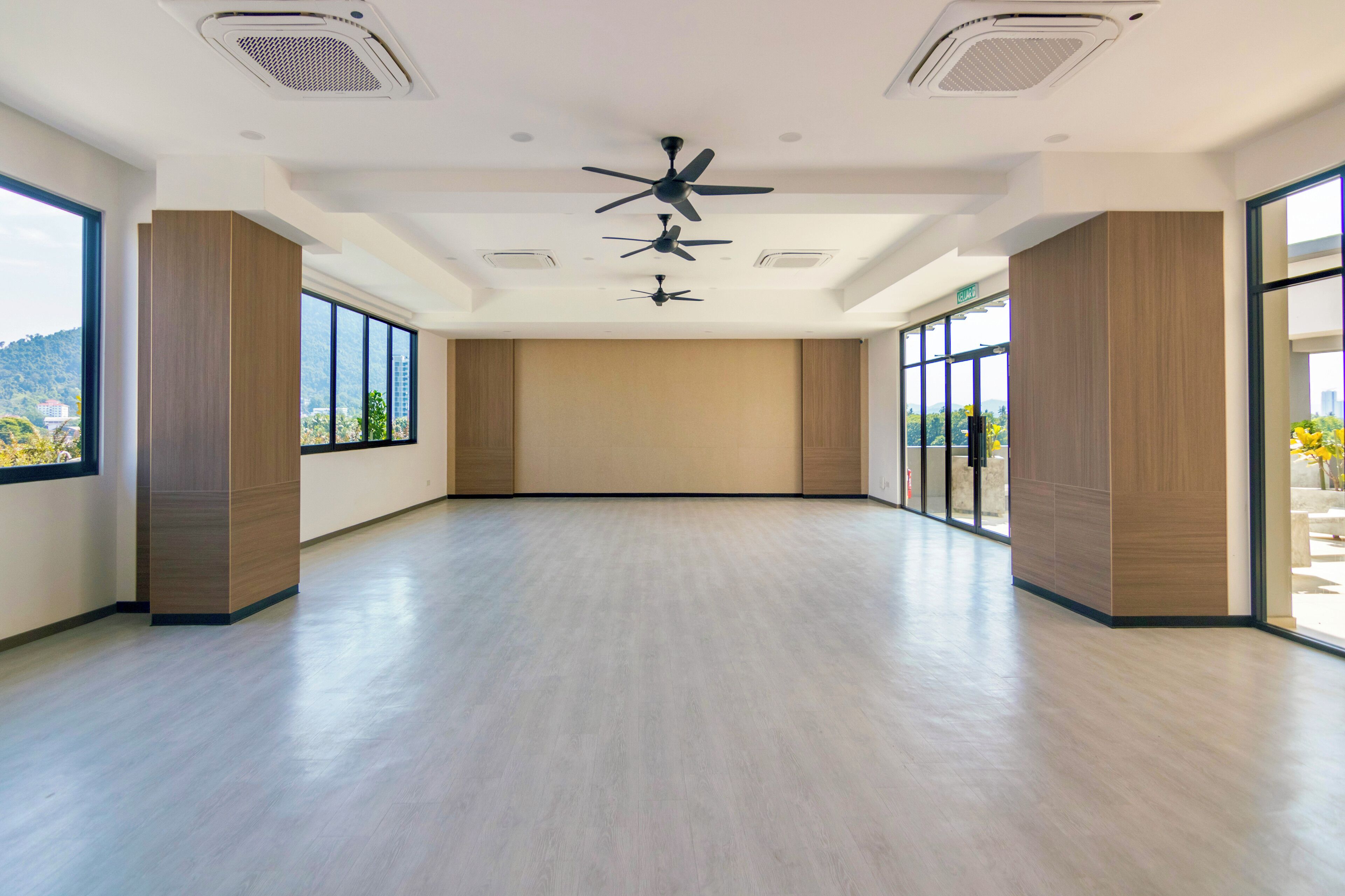 A spacious room with a high ceiling, large windows, and a central ceiling fan.