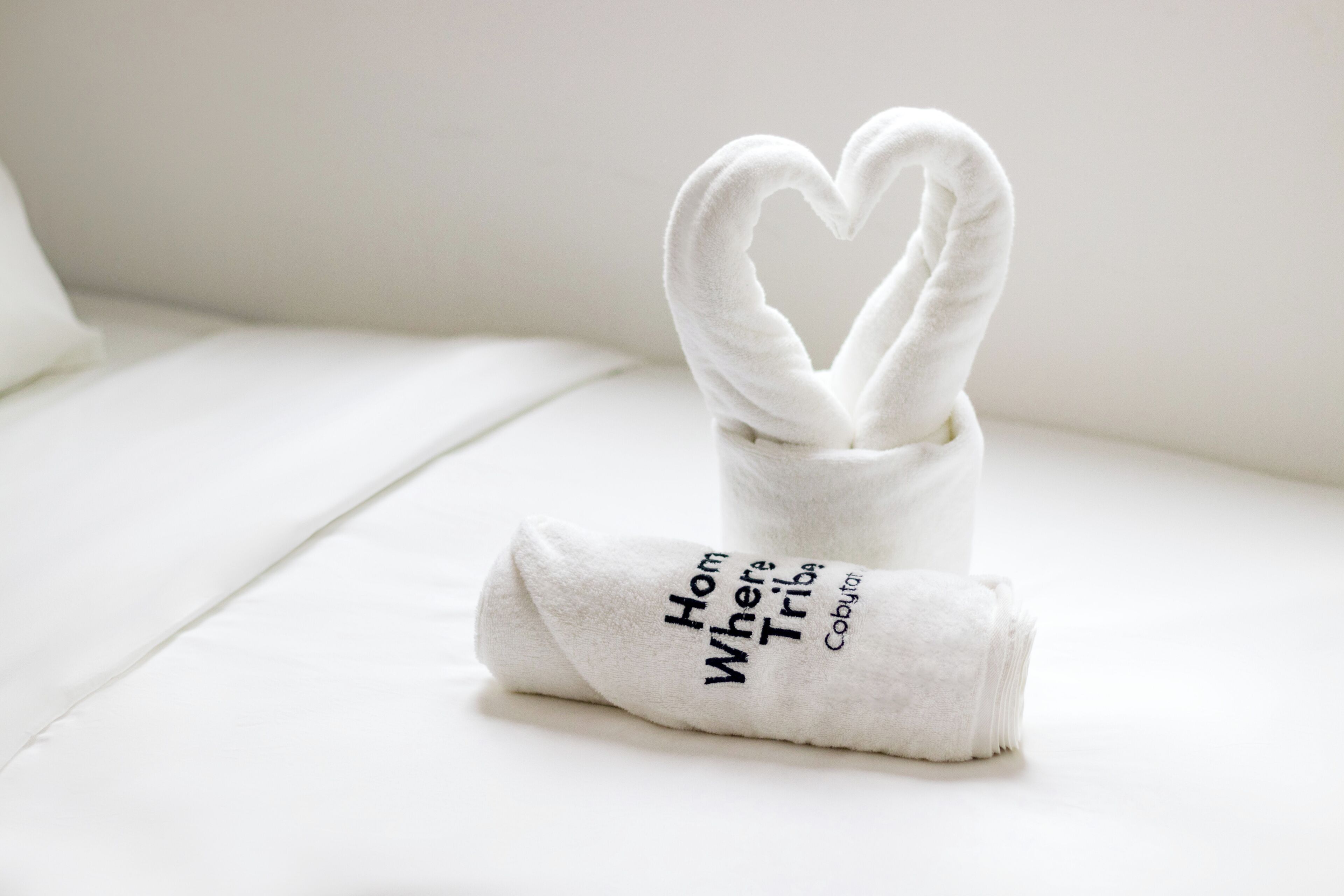 A neatly folded white towel with text on it placed on a white surface.