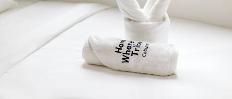 A neatly folded white towel with text on it placed on a white surface.