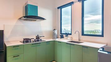 A modern kitchen with green cabinets, a stove, a sink, and a window with a city view.