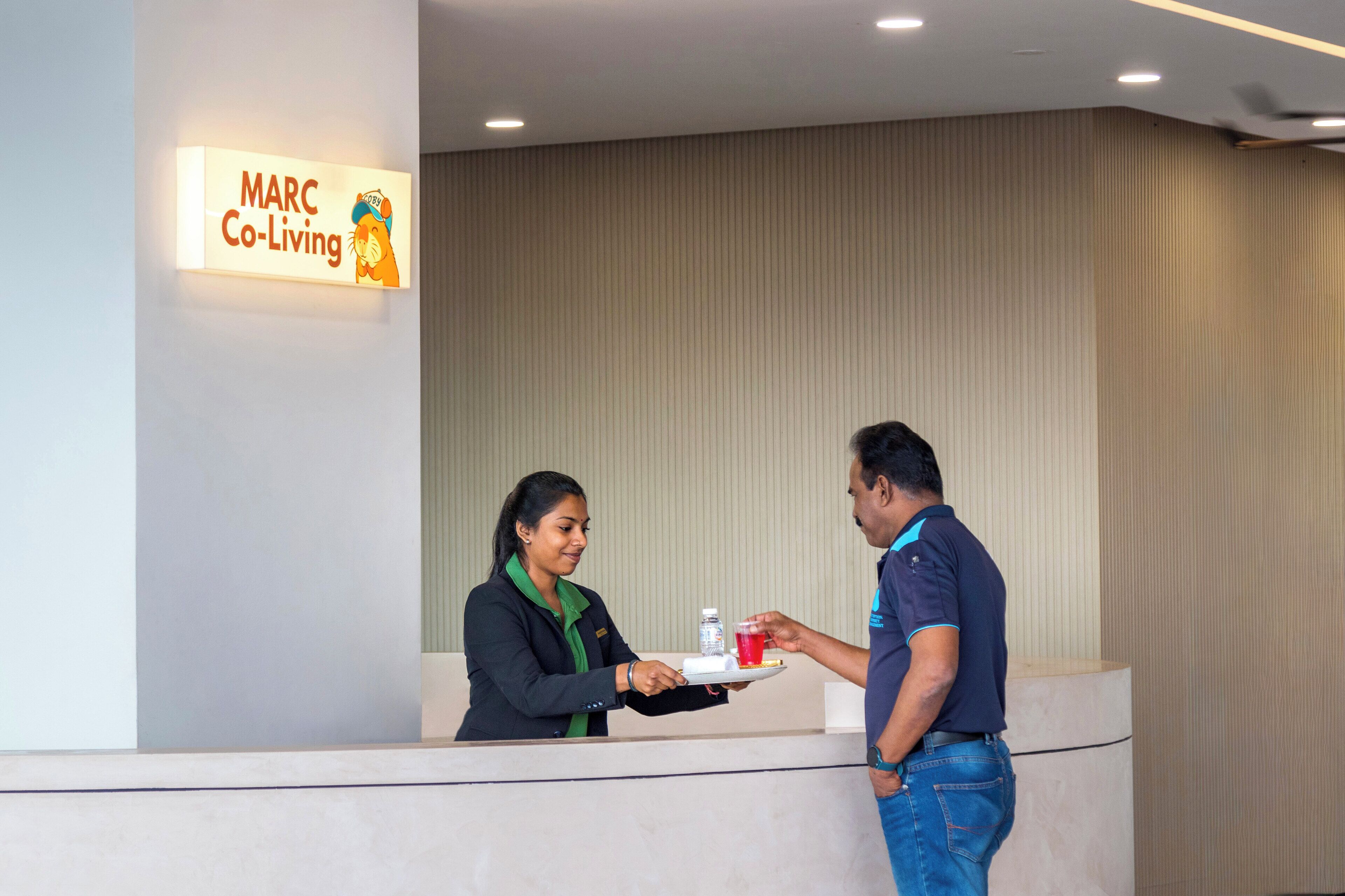 A reception desk with a sign reading "MARC Co-Living".