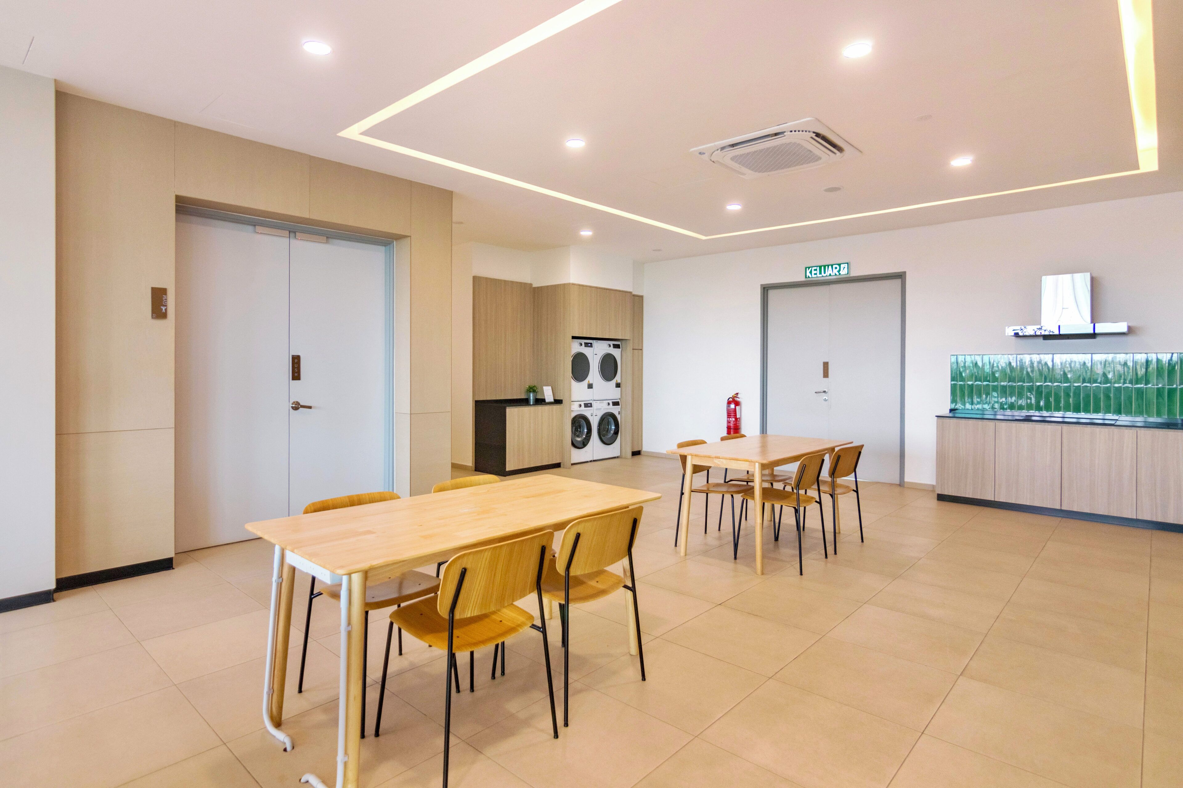 A modern dining area with wooden tables and chairs, a kitchen with appliances, and a fire extinguisher.
