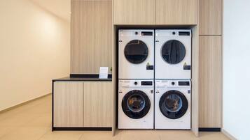 A laundry room with four stacked front-loading washing machines and a counter with a sign.