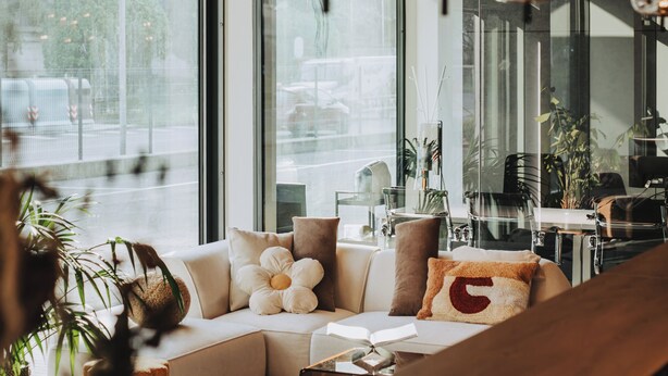 A modern interior with a sofa, a wooden table, and hanging pendant lights.