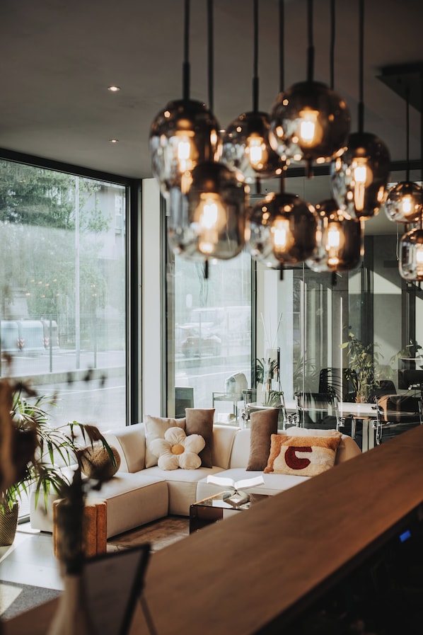 Ein modernes Interieur mit einer Couch, einem Holztisch und hängenden Pendelleuchten.
