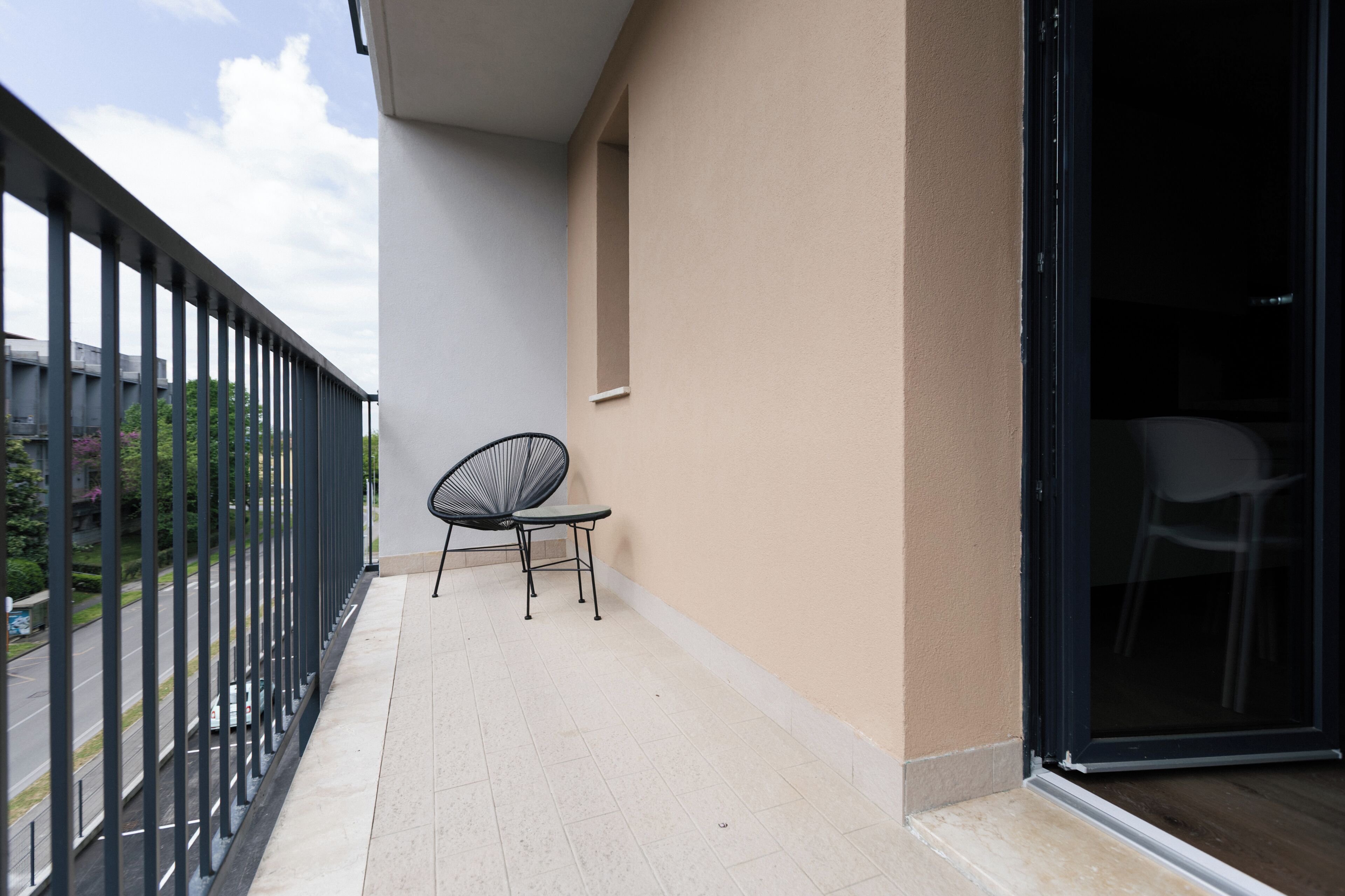 A balcony with a chair, a small table, and a glass door leading to an interior space.