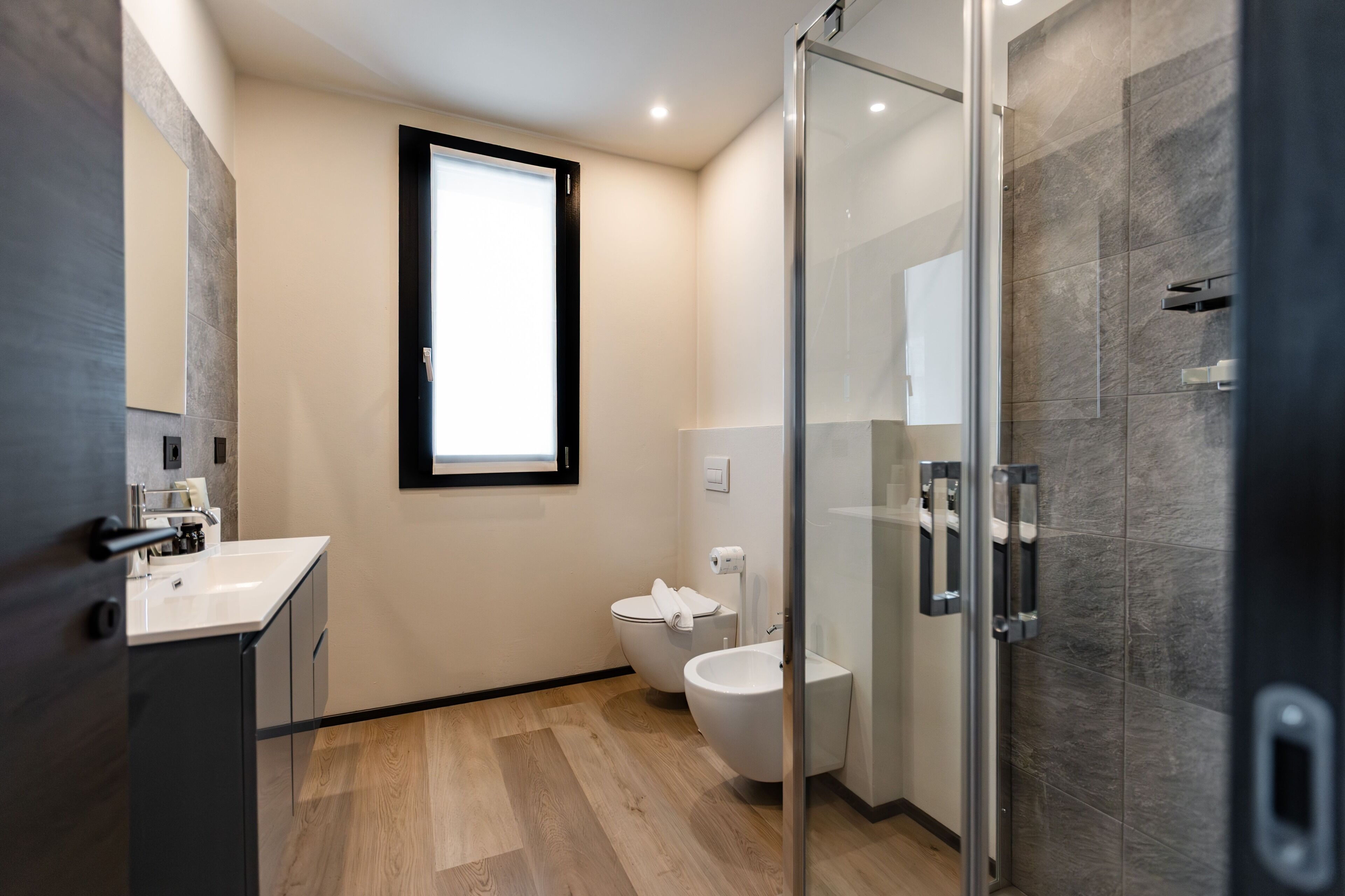 Ein modernes Badezimmer mit Duschkabine aus Glas, Toilette und Waschbecken.
