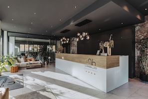 A reception desk with a modern design, a seating area with a sofa and coffee table, and a large window allowing natural light.