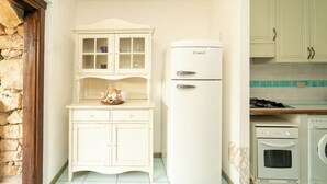 Cocina compacta con un refrigerador blanco, horno empotrado y una pequeña encimera.