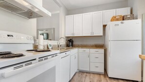 A kitchen with white cabinets, a white stove, a refrigerator, and a wooden floor. - 1035 Beachview Dr in Saint Simons Island, GA (Saint Simons Island)