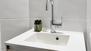 Een badkamer met een wit wastafel, een moderne kraan en een spiegel erboven.