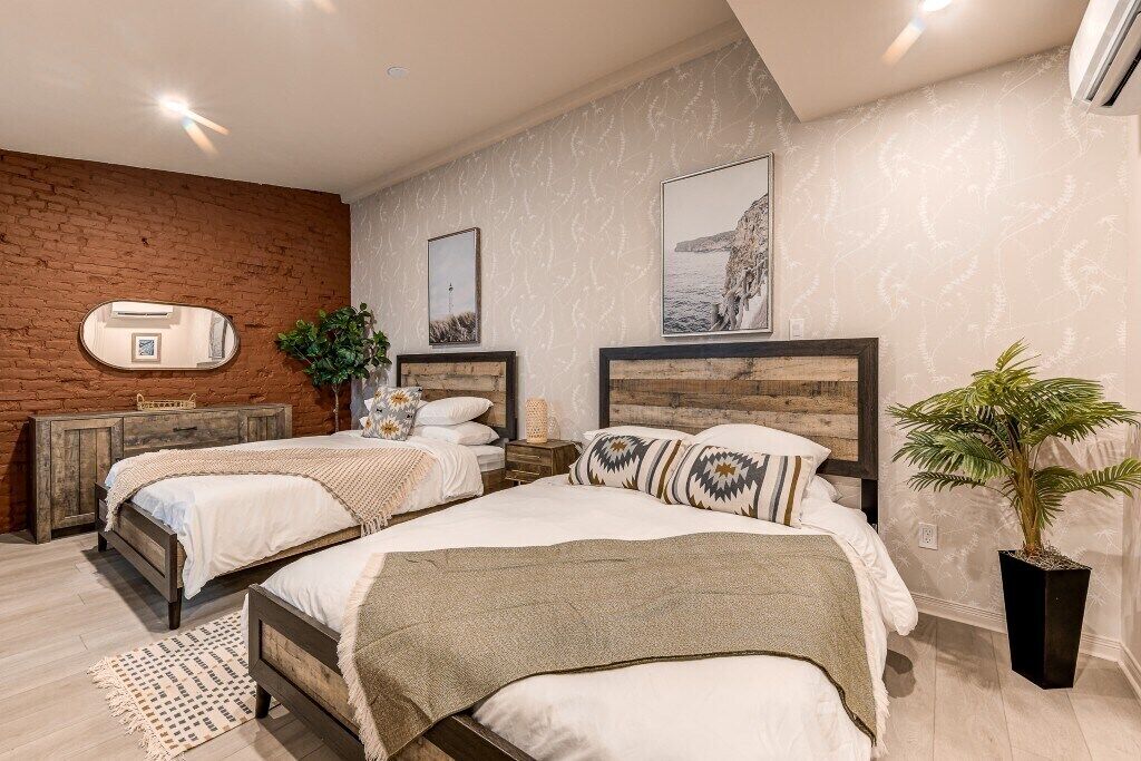 Een slaapkamer met twee bedden, een bakstenen muur en een grote spiegel.