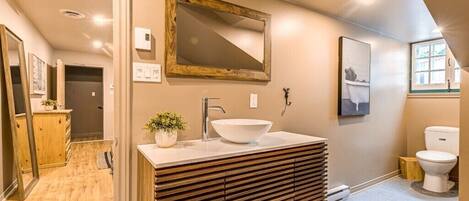 Un baño moderno con tocador de madera, un espejo grande y un lavabo blanco.
