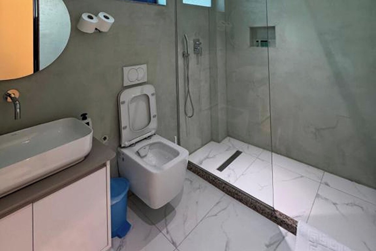 A modern bathroom with a sink, toilet, and glass-enclosed shower.