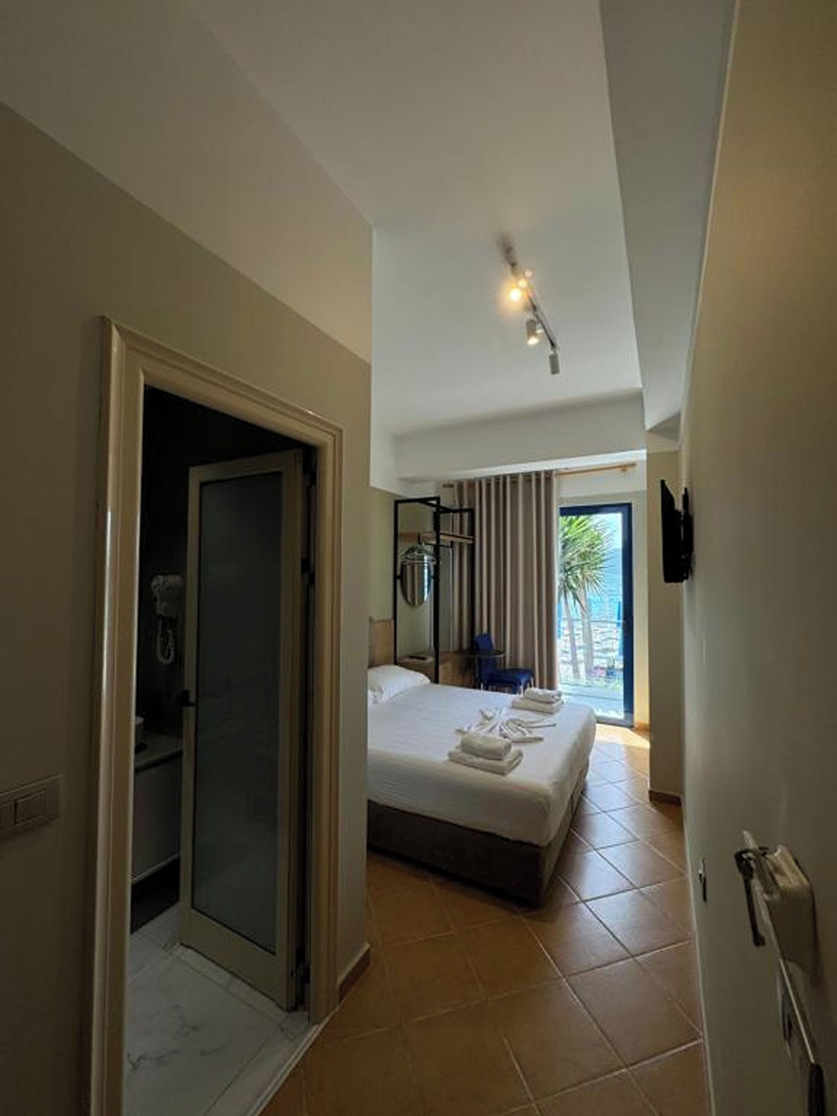 Ein Hotelzimmer mit Bett, Dusche, Balkon mit Aussicht und einem an der Wand befestigten Fernseher.
