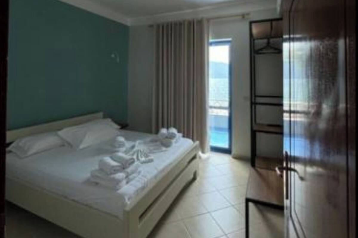 A bedroom with a bed, a wardrobe, and a view of the outdoors.