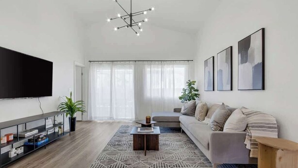 A modern living room with a flat-screen TV, a sofa, a coffee table, and a patterned rug. - Chic & Modern Home with Pool Table, BBQ, and MORE (North Las Vegas)