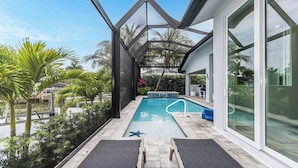 Un espace piscine extérieur moderne, doté d’une structure de toit aux lignes géométriques, offrant une vue dégagée sur la piscine et entouré de verdure.