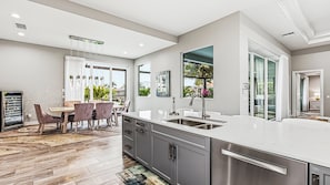 A modern kitchen with a large island, stainless steel appliances, and a dining area with a view.