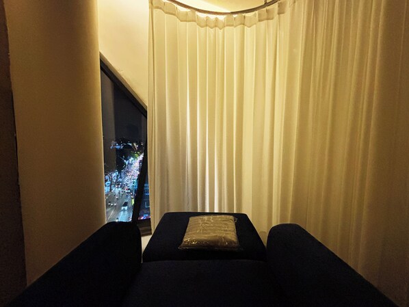 Une chambre avec un lit, une fenêtre avec des rideaux et une vue sur le paysage urbain la nuit.