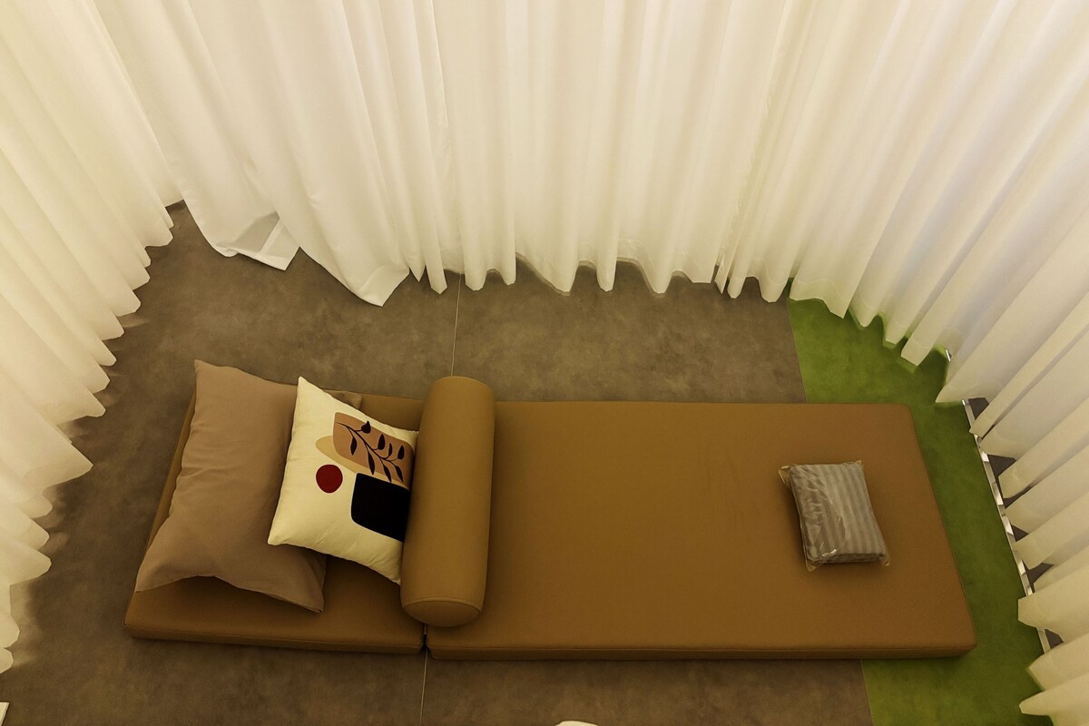 A room with a brown sofa, a pillow with a red circle, and a striped pillow.