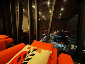 A modern hotel room with a city view, large windows, and orange seating. - Saigon Travel Lounge (Ho Chi Minh City)