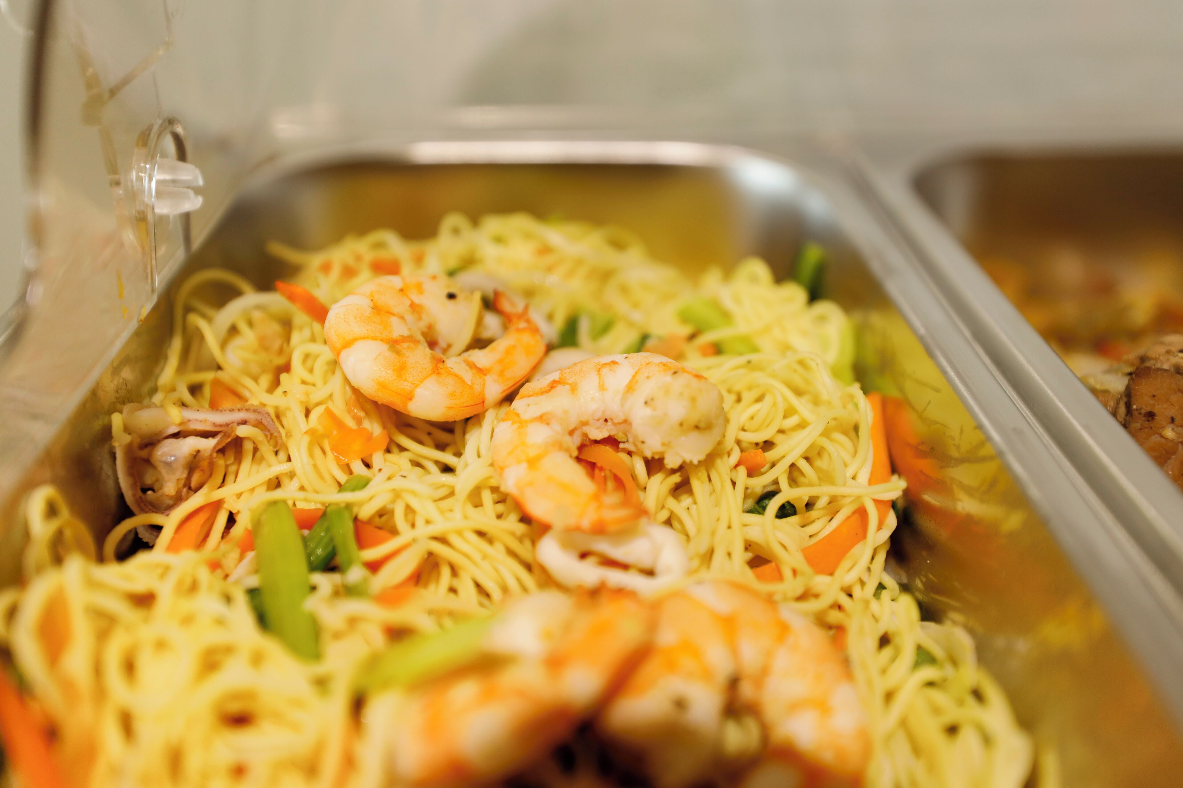 Un buffet proposant des nouilles, des crevettes et des légumes.