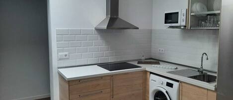 Een koelkast, een magnetron, een kookplaat, kookgerei, borden en bestek