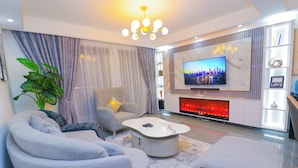 A modern living room with a sofa, armchair, coffee table, and a flat-screen TV mounted on the wall. - 2 Bed Apartment Sleeps 4 - Balcony, Parking, Wifi (Nairobi)