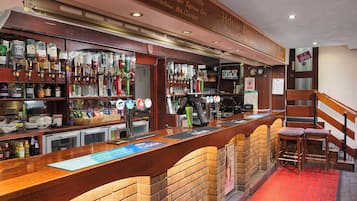Eine Bar mit einer Ziegel-Theke, Regalen voller Spirituosenflaschen und Hockern.
