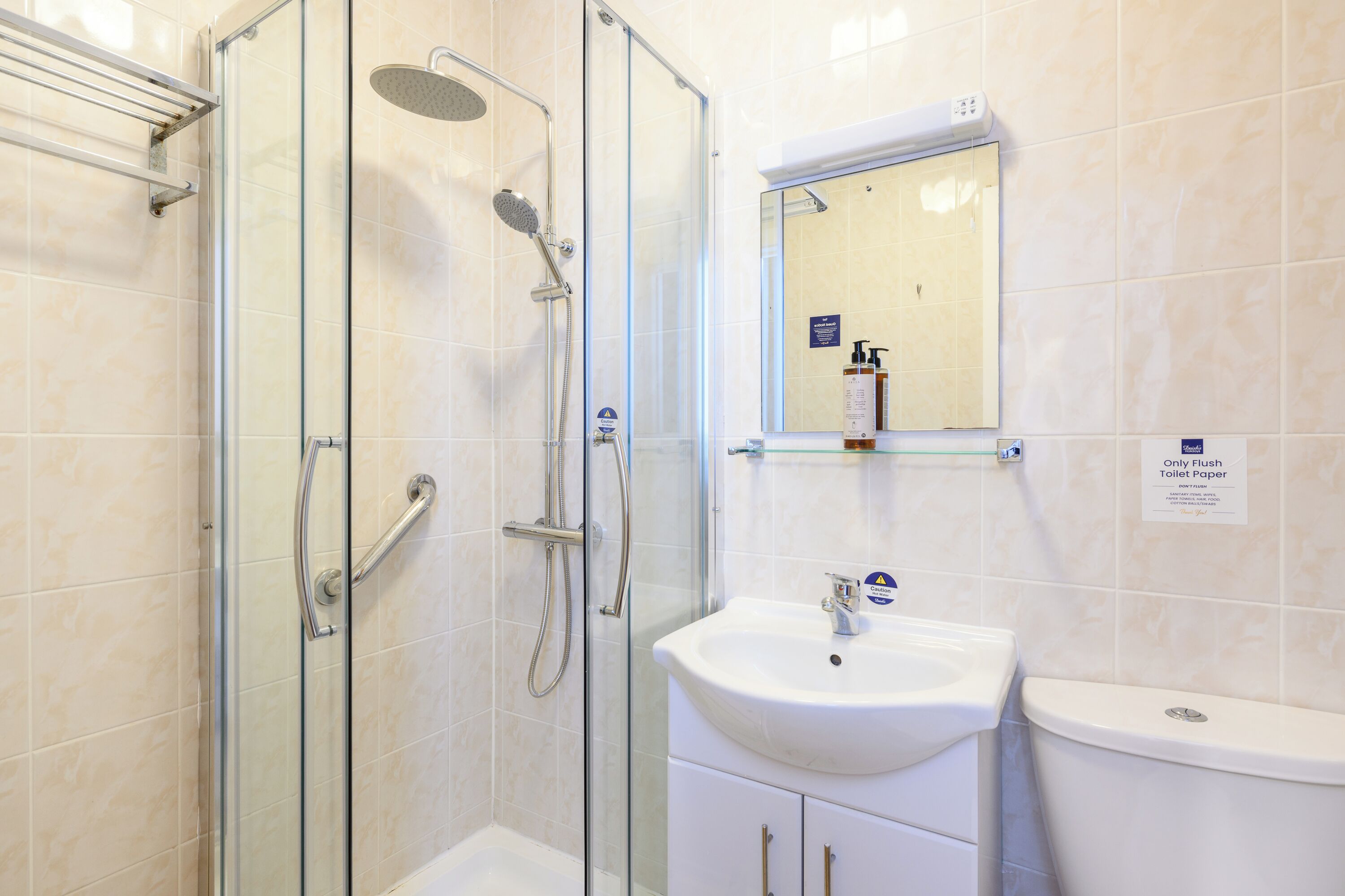 A bathroom with a glass-enclosed shower, a white sink, and a toilet.