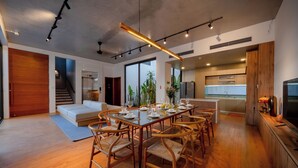 A modern dining area with a long table set for six, surrounded by wooden chairs.