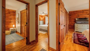 A hallway with wooden walls and floors, leading to a bedroom with a bed and a dresser. - Scenic 4BR retreat with valley views, minutes from Blacksburg and Lane Stadium, sleeps 12 (Blacksburg)